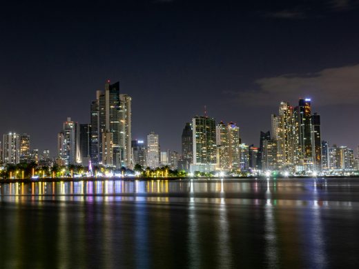 Stunning view of Panama City skyline illuminated at night, reflected on calm waters.