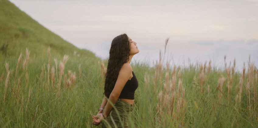 A woman stands in the lush fields of Anton Valley, Panama, basking in the natural beauty.