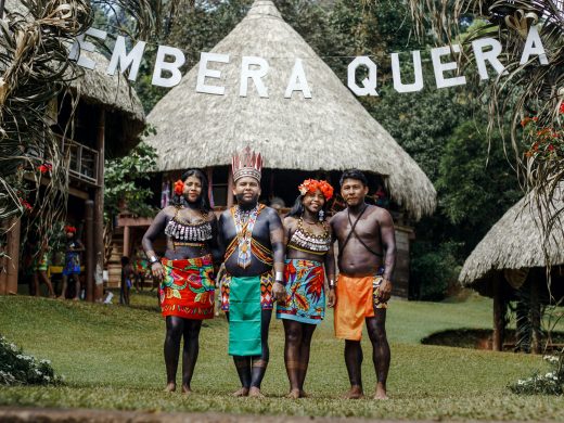 Group portrait of Embera Quera people in traditional attire at their village.