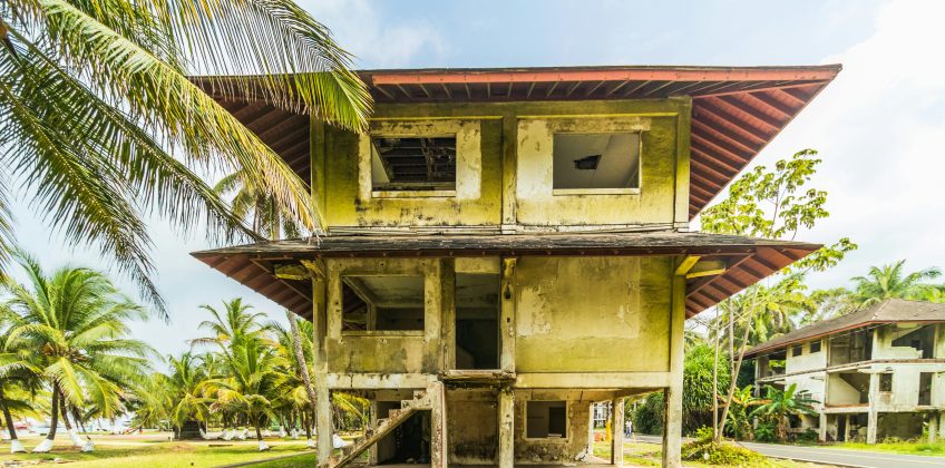 Dilapidated colonial structure amidst tropical palms in Colón, Panama.